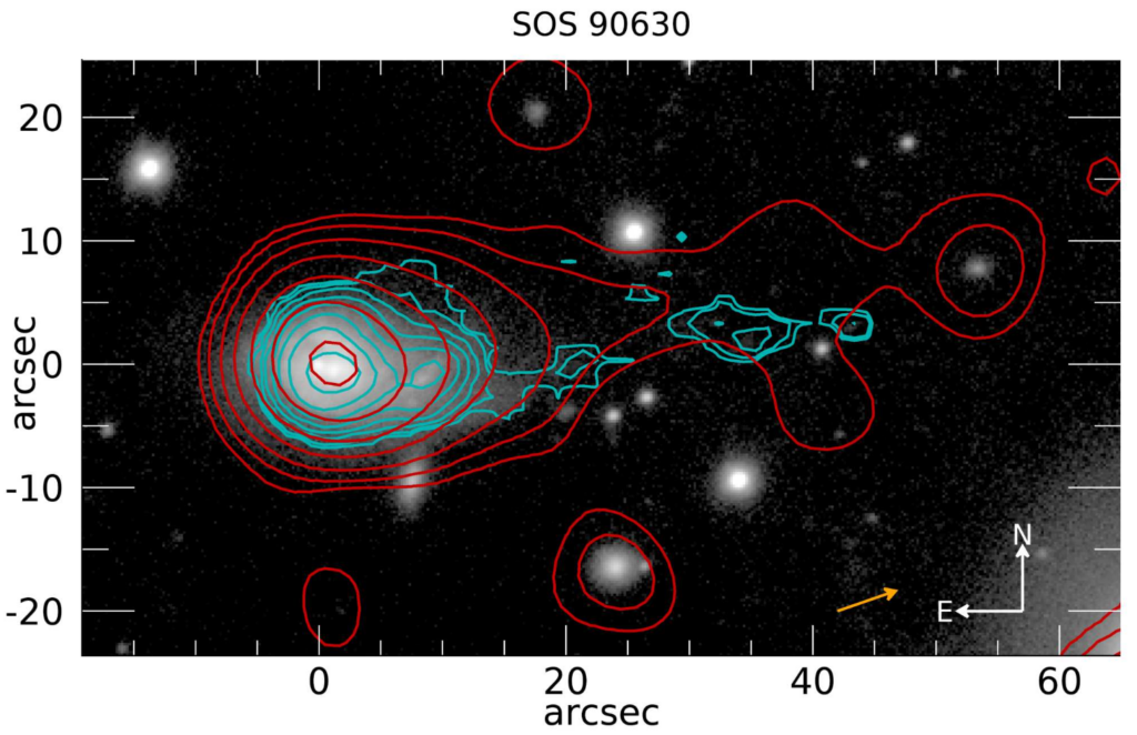 The background is a black and white image of galaxies, which appear as white bright spots. On the left side, there is a larger galaxy. Over top the image are red and cyan contours. They follow the shape of the large galaxy and extend further to the left side of the image.